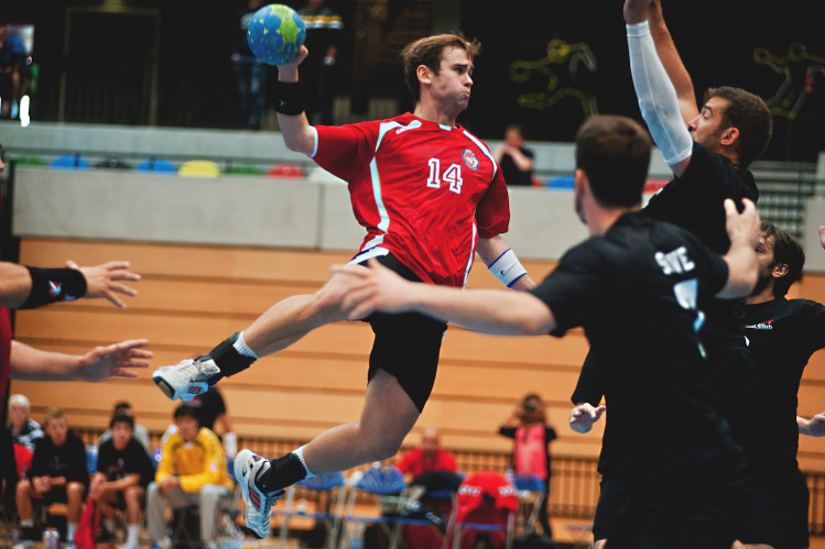 man holding ball while jumping near three mne
